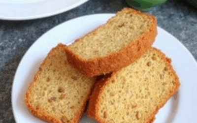 Budín de zanahoria y avena servido en un plato con nueces encima, acompañado de una taza de café y frutas frescas